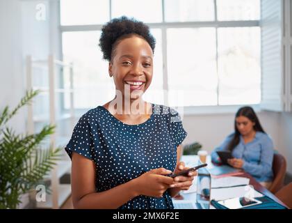 Portrait of young Black business woman laughing using cellphone in office space Stock Photo