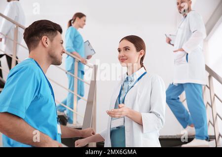 Female doctor talking to colleague on staircase in clinic Stock Photo