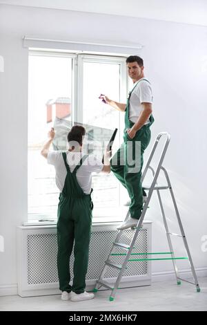 Professional workers tinting window with foil indoors Stock Photo