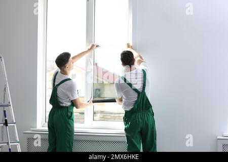 Professional workers tinting window with foil indoors Stock Photo