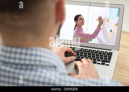 Young man watching video at desk, closeup. Online learning Stock Photo