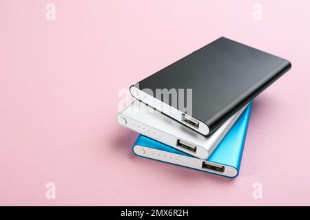 Modern external portable chargers on pink background Stock Photo