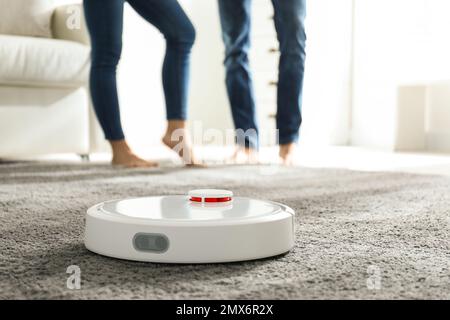 Couple using robotic vacuum cleaner at home Stock Photo