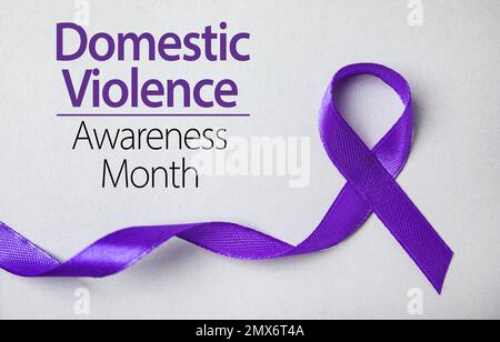 Purple ribbon on grey background, top view. Symbol of Domestic Violence Awareness Stock Photo