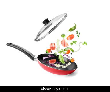 Different vegetables falling into frying pan on white background. Process of cooking Stock Photo