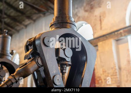 Fragment of steam engine from 1903. Important part of technological line in historical factory. Shabby, devastated walls and arcade window in the back Stock Photo