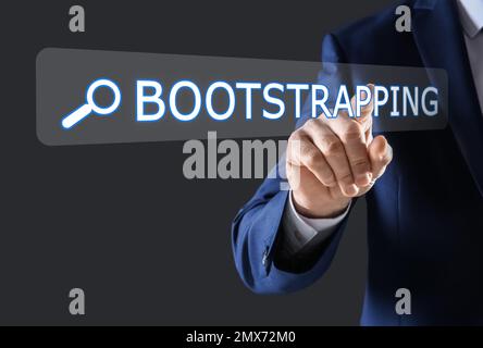 Businessman touching virtual screen with word BOOTSTRAPPING in search bar against dark background, focus on hand Stock Photo