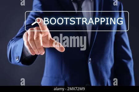 Businessman touching virtual screen with word BOOTSTRAPPING in search bar against dark background, focus on hand Stock Photo