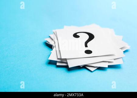 Heap of paper notes with question marks on light blue background, closeup Stock Photo