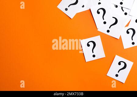 Paper notes with question marks on orange background, flat lay. Space for text Stock Photo
