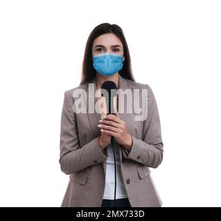 Young journalist with microphone wearing medical mask on white background. Virus protection Stock Photo