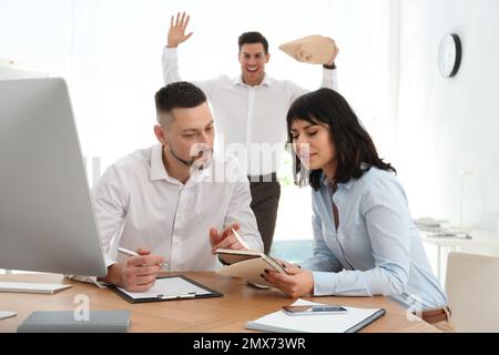Man popping paper bag behind his colleagues in office. April fool's day Stock Photo