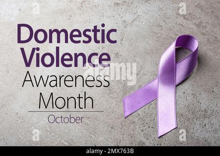 Purple ribbon on grey background. Symbol of Domestic Violence Awareness Stock Photo