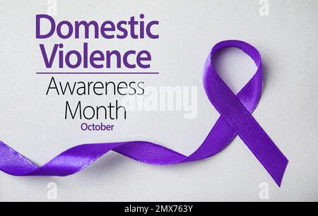 Purple ribbon on grey background, top view. Symbol of Domestic Violence Awareness Stock Photo