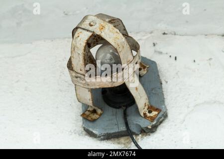 Outdoor incandescent lamp in a protective anti-theft rusty cage. Stock Photo