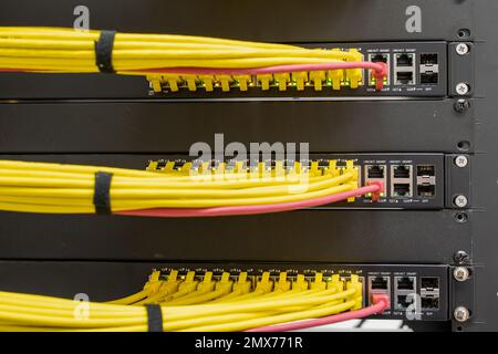 Selective focus on neat and tidy patched network cables, RJ45, connected to the switches and routers mounted on the rack in data centre, networking Stock Photo