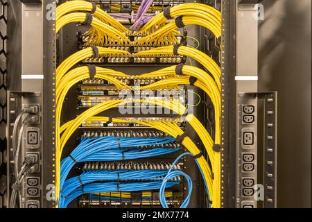Rack with power sockets on a side, multiple switches and routers with tidily patched network cables, RJ45, data centre, networking Stock Photo