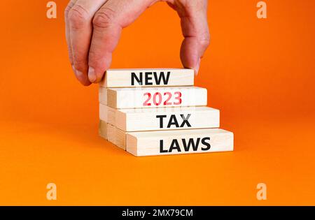 New 2023 tax laws symbol. Concept words New 2023 tax laws on wooden blocks. Beautiful orange table orange background. Businessman hand. Business new 2 Stock Photo