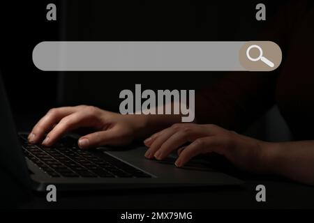 Search bar of internet browser and woman working with laptop in darkness, closeup Stock Photo