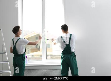 Professional workers tinting window with foil indoors Stock Photo