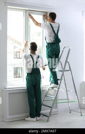 Professional workers tinting window with foil indoors Stock Photo