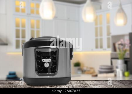 Modern electric multi cooker on wooden table in kitchen. Space for design Stock Photo