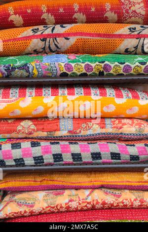 Colorful blankets and quilts placed in a stack in bright and vibrant orange and red colors Stock Photo