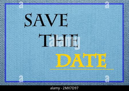 Phrase SAVE THE DATE on light blue jeans fabric, top view Stock Photo