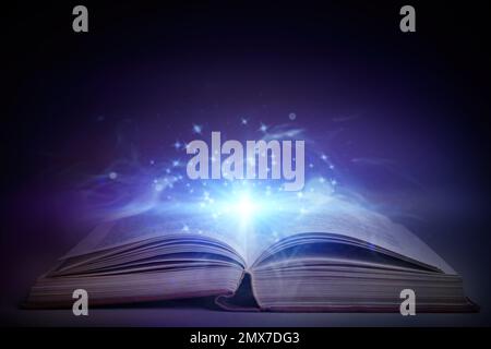Open book with magic glowing on table. Fairy tale Stock Photo