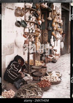 Tunis, Tunisia a fruit and vegetable merchant in front of a pottery shop in a medina souk , 1909 or 1910 - Algeria, Tunisia - Jules Gervais -Courtellemont and Souvieux Stock Photo
