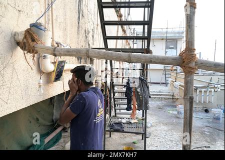 INDIA, Mumbai, apartment tower under renovation, bamboo scaffold, migrant worker from UP and Bihar doing paint works, during the work period they are living on the roof / INDIEN, Mumbai, Wohnhaus mit Baugerüst aus Bambus, Wanderarbeiter aus UP und Bihar bei Malerarbeiten, während der Arbeitsphase wohnen sie auf dem Dach Stock Photo