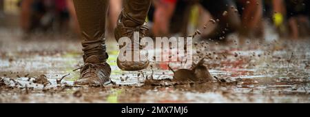 Mud race runners.Crawling,passing under a barbed wire obstacles during extreme obstacle race Stock Photo
