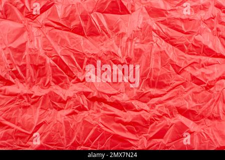 Texture of crumpled transparent polyethylene on a pink, red background, full frame Stock Photo