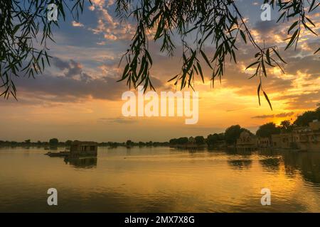 Beautiful sunset at Gadisar lake, Jaisalmer, Rajasthan, India. Setting sun and colorful clouds in the sky with view of the Gadisar lake. Stock Photo