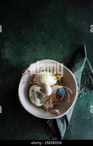 Top view of easter holiday dinner set with colored eggs surrounded with flowers on concrete table Stock Photo