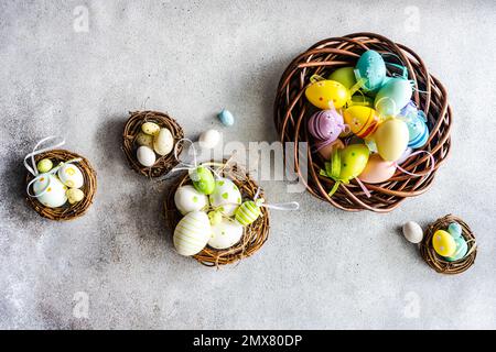 Top view easter holiday card with wreathes full of multicolor eggs on concrete background Stock Photo