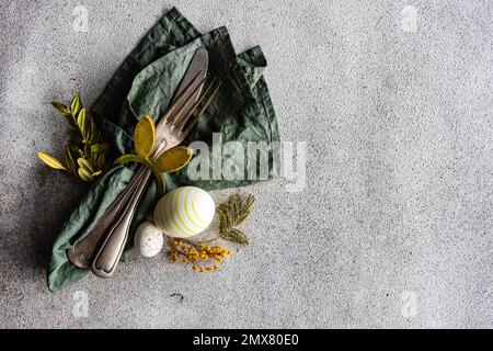 From above place setting for Easter dinner in green color on concrete background Stock Photo
