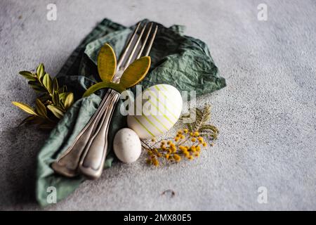From above place setting for Easter dinner in green color on concrete background Stock Photo