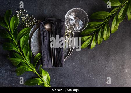 Top view of rustic summer table setting with plate and cutlery decorated with cushion baby's-breath and italian ruscus leaves Stock Photo