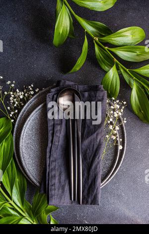 Top view of rustic summer table setting with plate and cutlery decorated with cushion baby's-breath and italian ruscus leaves Stock Photo