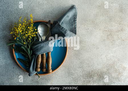 Festive table setting for Easter holiday dinner with bright yellow mimosa flowers on concrete table Stock Photo