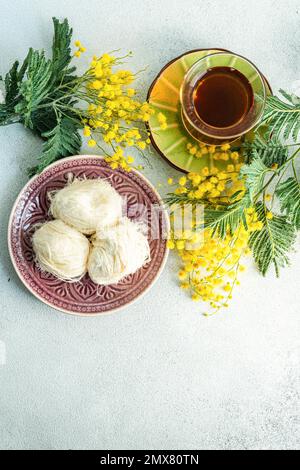 Turkish delight and tea on the table with yellow mimosa flowers Stock Photo