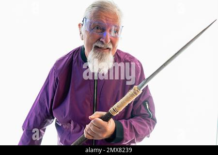 Smiling elderly bearded male hipster in glasses standing against white background with sharp sword Stock Photo