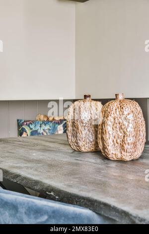 Set of decorative vases placed on gray table near chair against white wall in kitchen Stock Photo