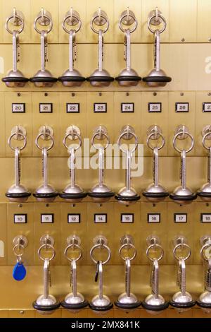 Three rows of old-fashioned metal hotel keys with a lone blue key Stock Photo