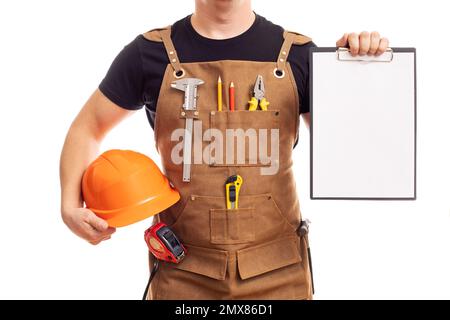 Male worker or builder in apron with helmet holding a clipboard Stock Photo