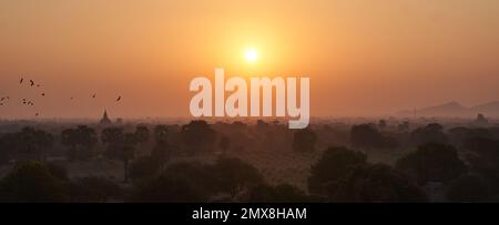 Sunrise in Bagan, Myanmar (Burma) with birds flying over ancient temples. Stock Photo