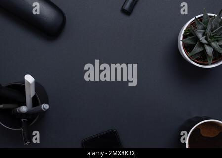 Work space with office supplies and a clear copy space in the middle. Black desk composition, top view, flat lay Stock Photo