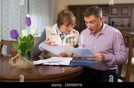 Man with elderly mother discussing documents Stock Photo