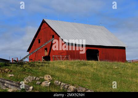 Hay elevator sits inside loft window on a rustic, red, wooden barn in Tennessee. Stock Photo